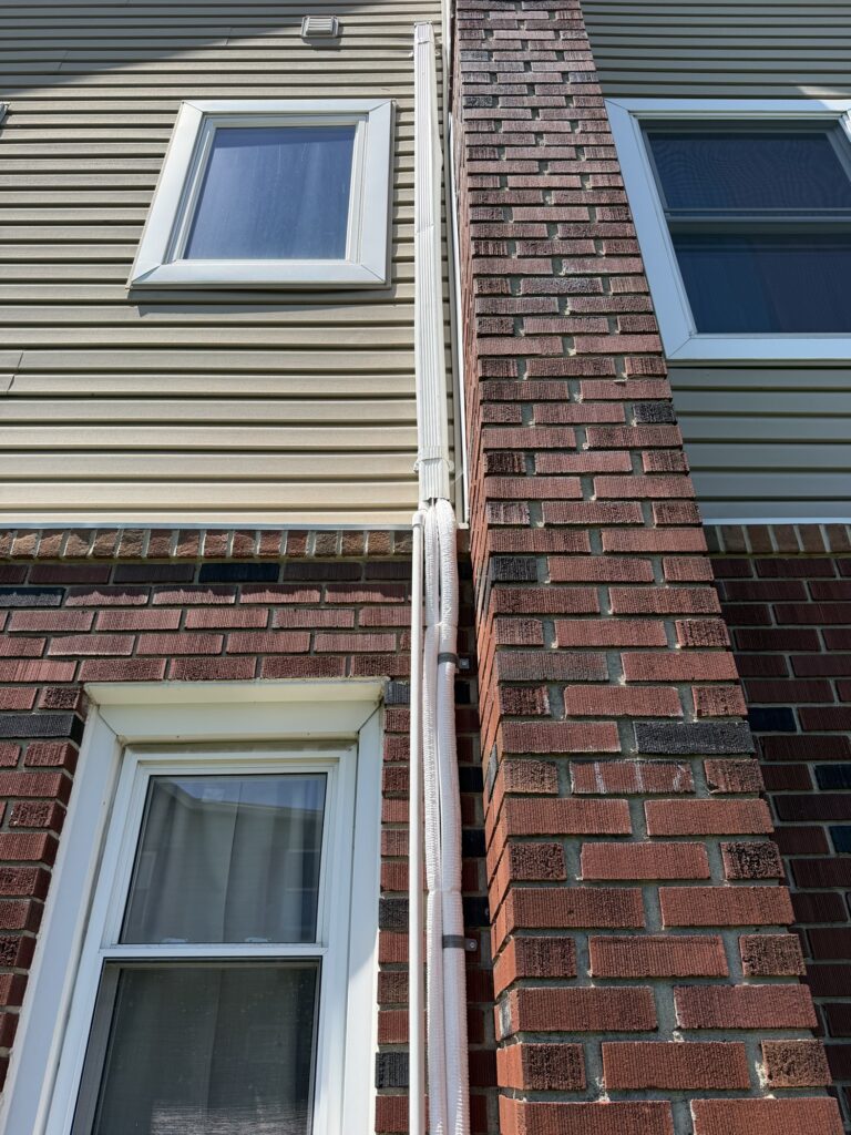 New air conditioning line set installed on the exterior wall of a Lehigh Valley home by Plumbing Pros